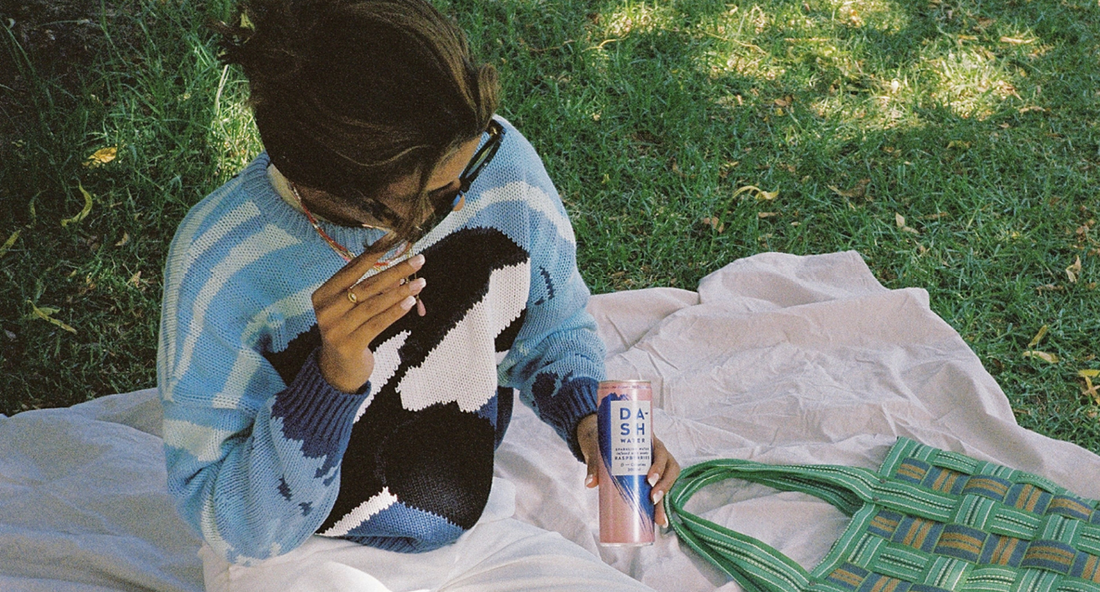 Girl on a picnic blanket drinking DASH